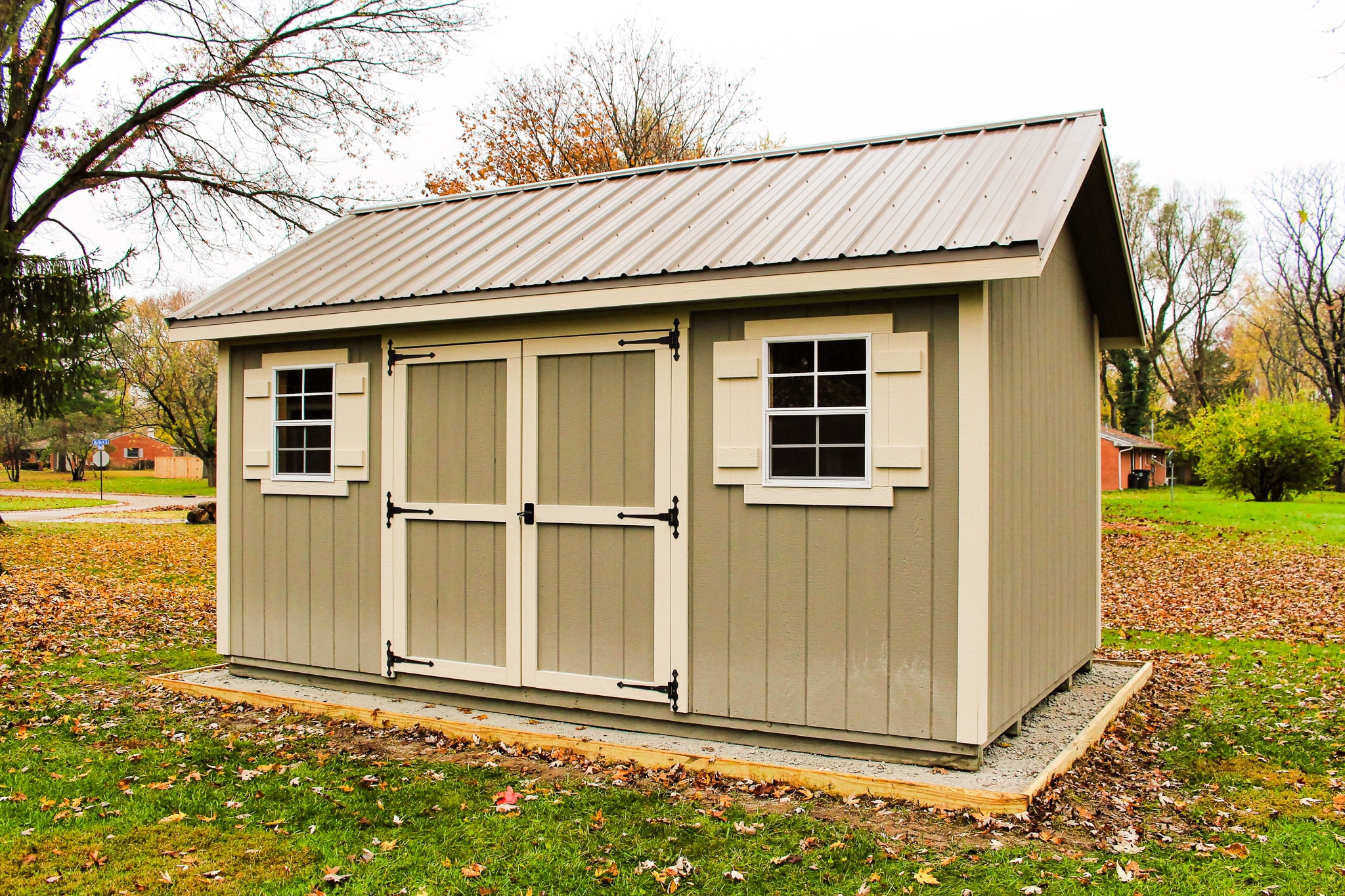 One of our beige gable sheds in Upper Arlington OH - Tan wood siding with cream colored trimmed double doors corners and shutters on two windows under tan metal roof