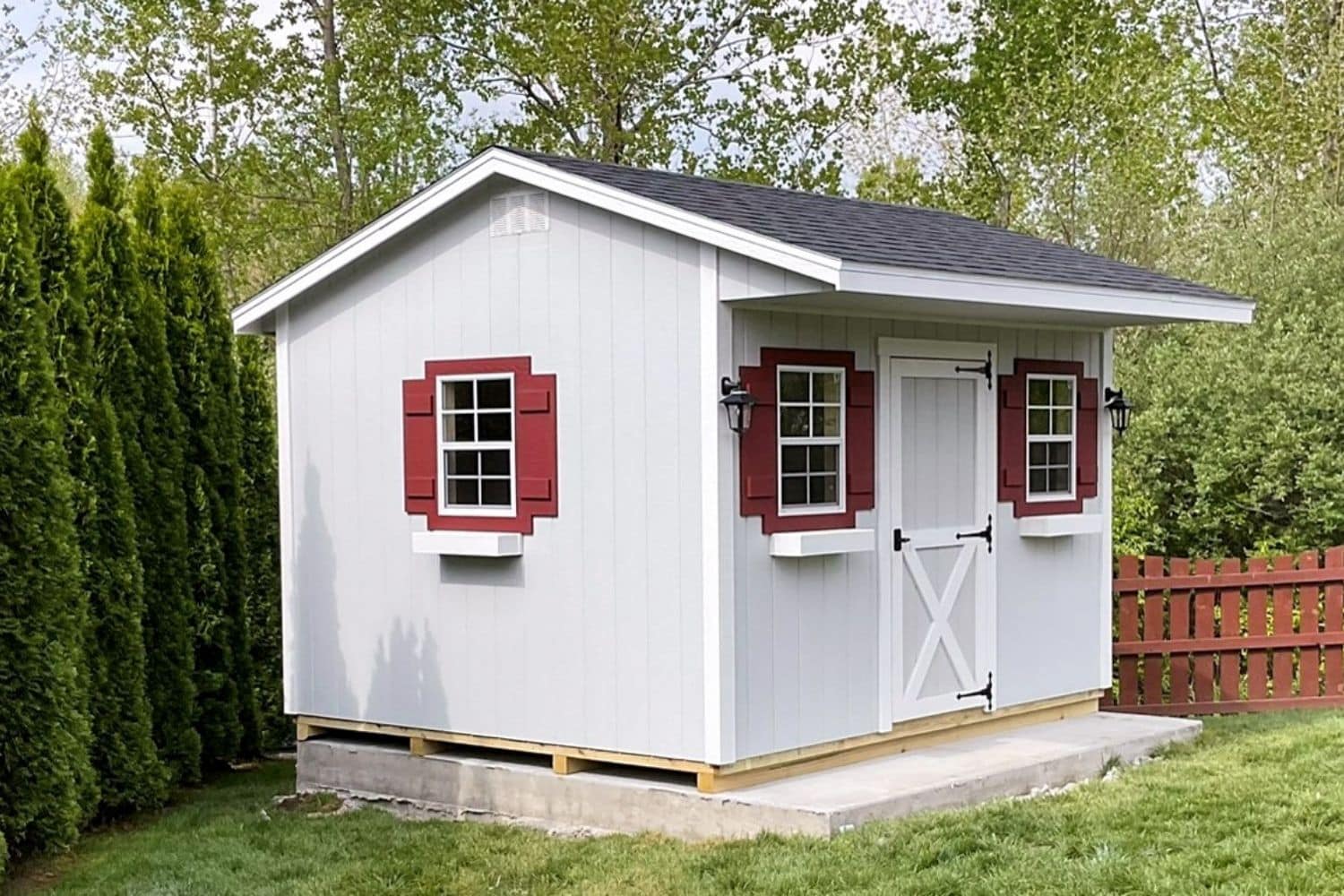 Backyard shed converted into an outdoor bar with red shutters and gray siding in Ohio.