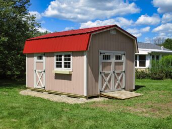 One of our highwall sheds for sale in Dublin OH - Peach siding white trimmed single and double doors and windows - red roof against a blue clouded sky on a sun-lit grassy yard