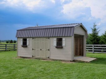 One of our highwall garage sheds for sale in Dublin OH - Beige siding with tan doors brown roof and window frames - open overhead door - cloudy day over fenced grassy field