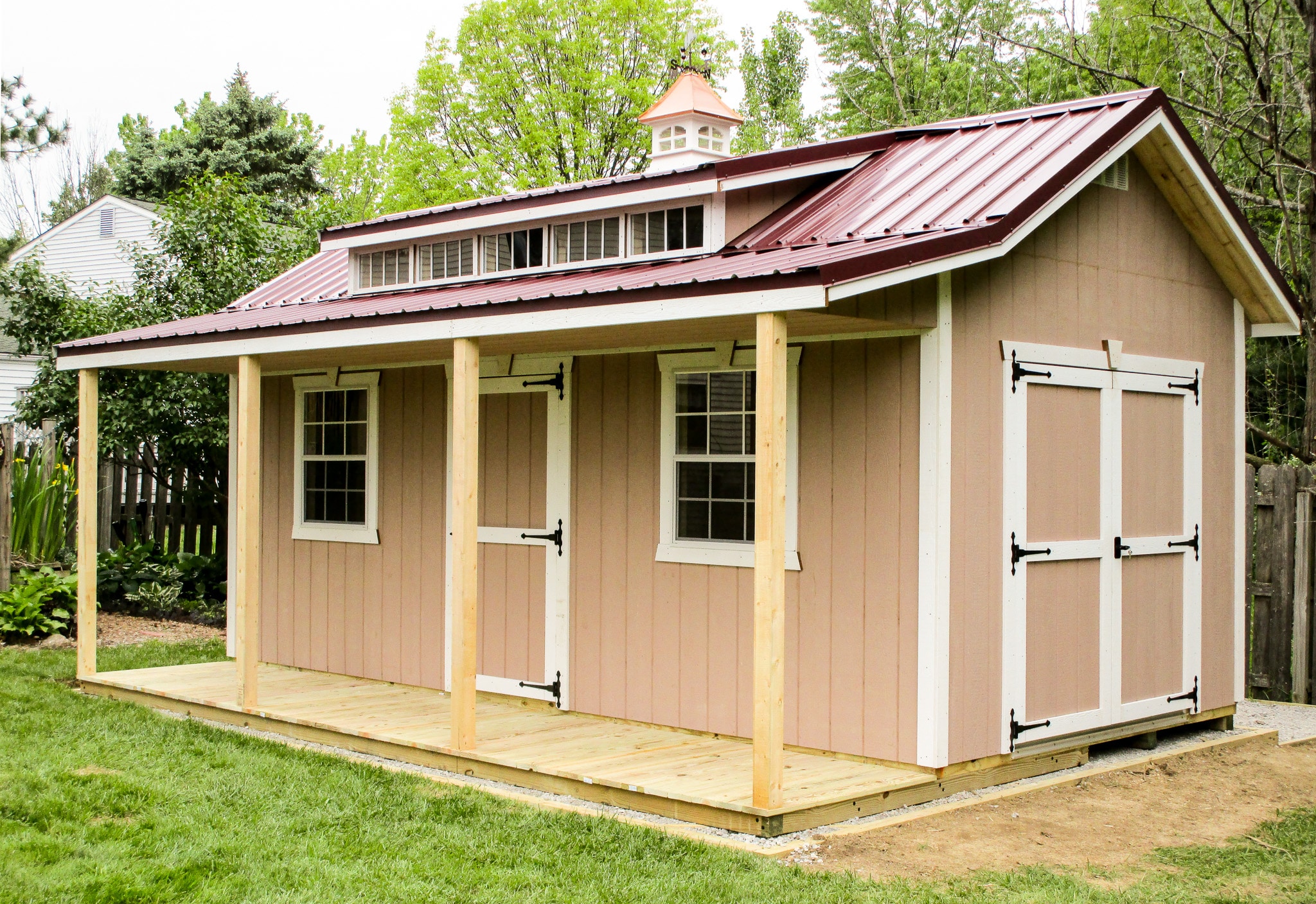 Custom shed with tan siding, white trim, and front porch built in Ohio.